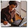 woman writing next to laptop